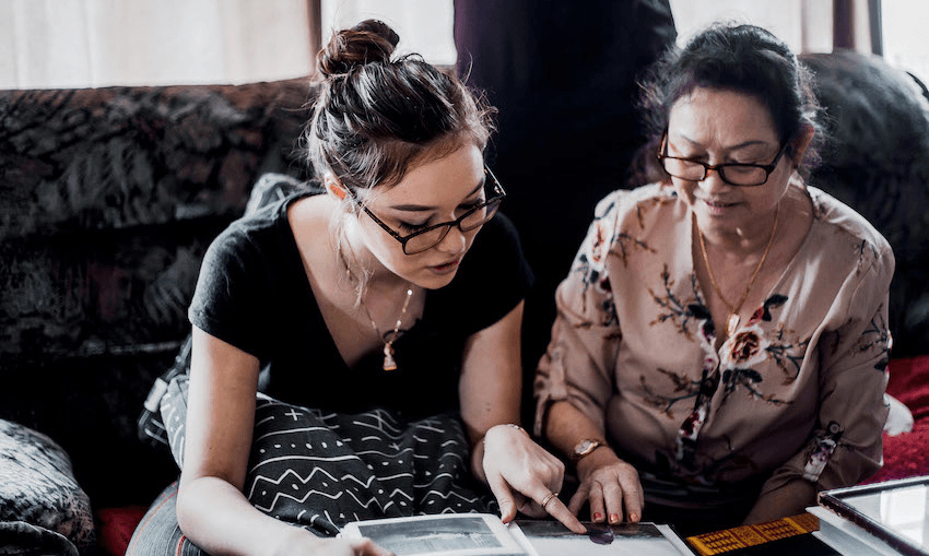 Emrie Meng looks at photo albums with her grandmother Mom Meng in Lower Hutt, Wellington. (Photo: Saraid de Silva / Julie Zhu) 
