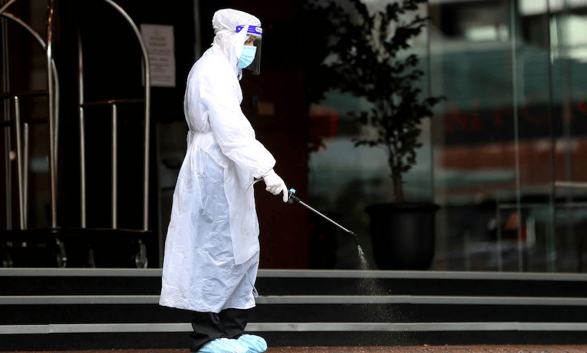 A hotel staff worker sanitises the outside of Stamford Plaza on July 10, 2020 in Auckland. (Photo: Hannah Peters/Getty Images) 
