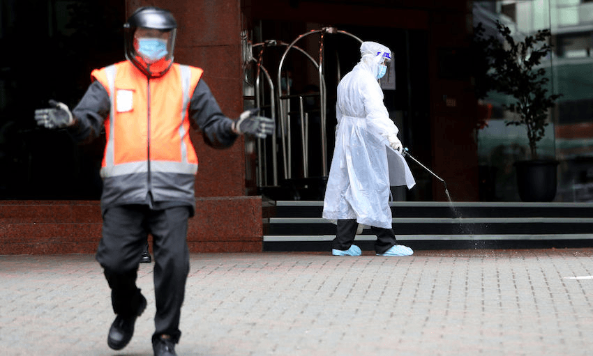 A hotel staff worker sanitises the outside of Auckland’s Stamford Plaza on July 10, 2020 (Photo: Hannah Peters/Getty Images) 
