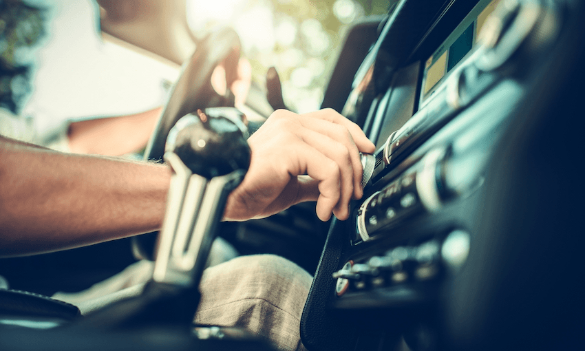 person adjusting dial on car radio