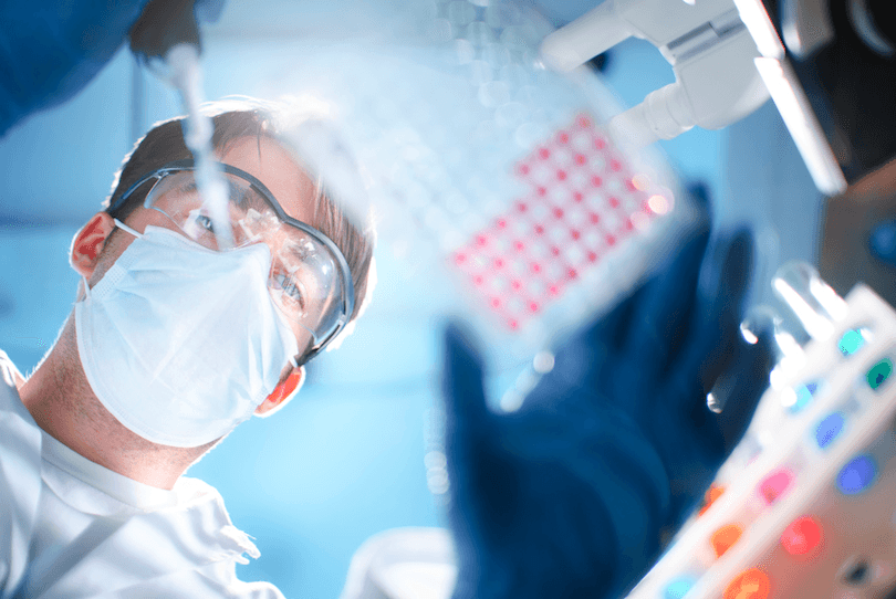 View from beneath glass table, of scientist examining a microtiter plate