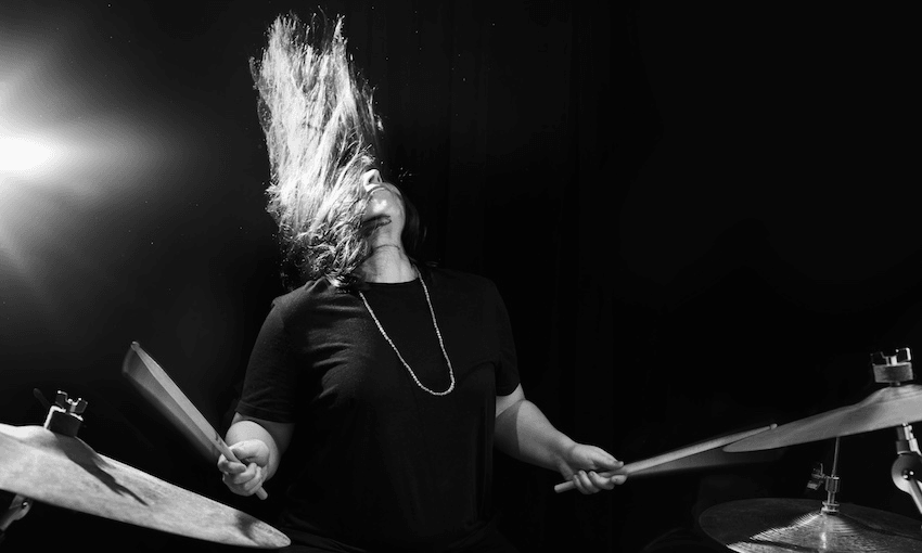 Black and white photo of a young woman rocking out on drums