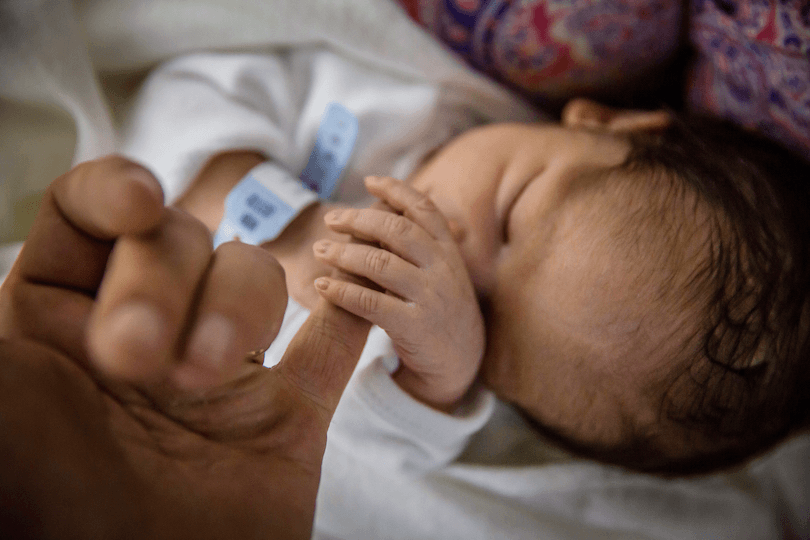 Newborn baby gripping his mothers hand