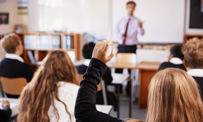 Female Student Raising Hand To Ask Question In Classroom