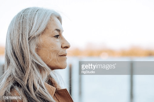 Portrait of a thoughtful mature woman standing on the beach and looking at the distance. 
